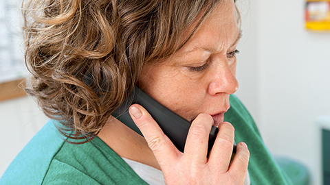 A woman on the telephone. (Link: Information about Helpline.)